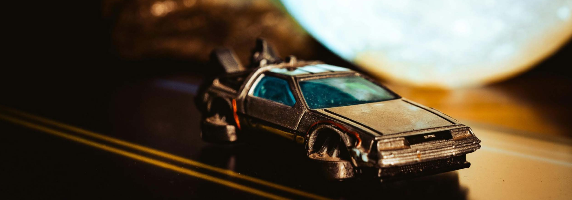 Model car of the DeLorean from Back to the Future on a dark road.